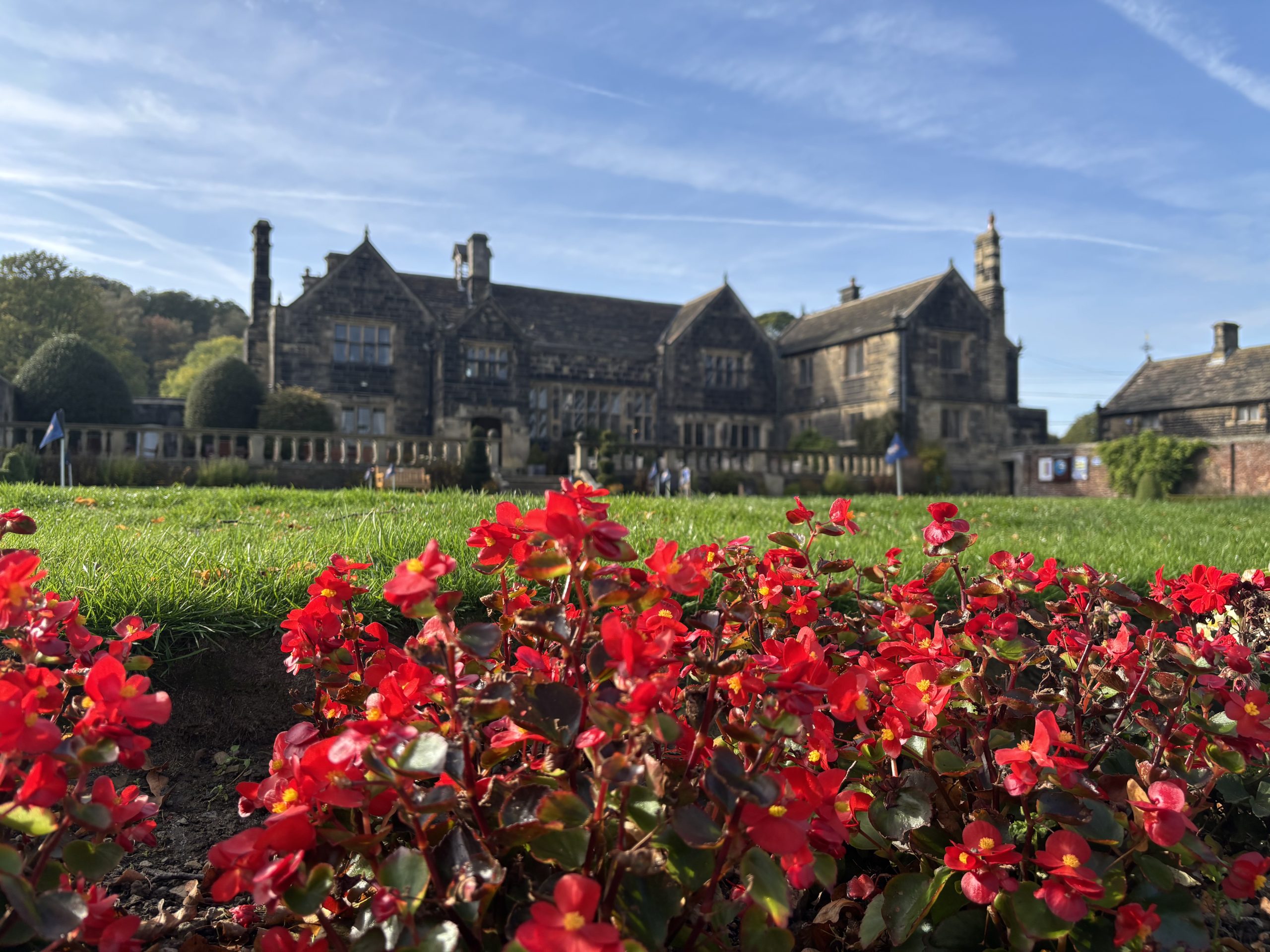 picture of large golf club house beyond red flowers